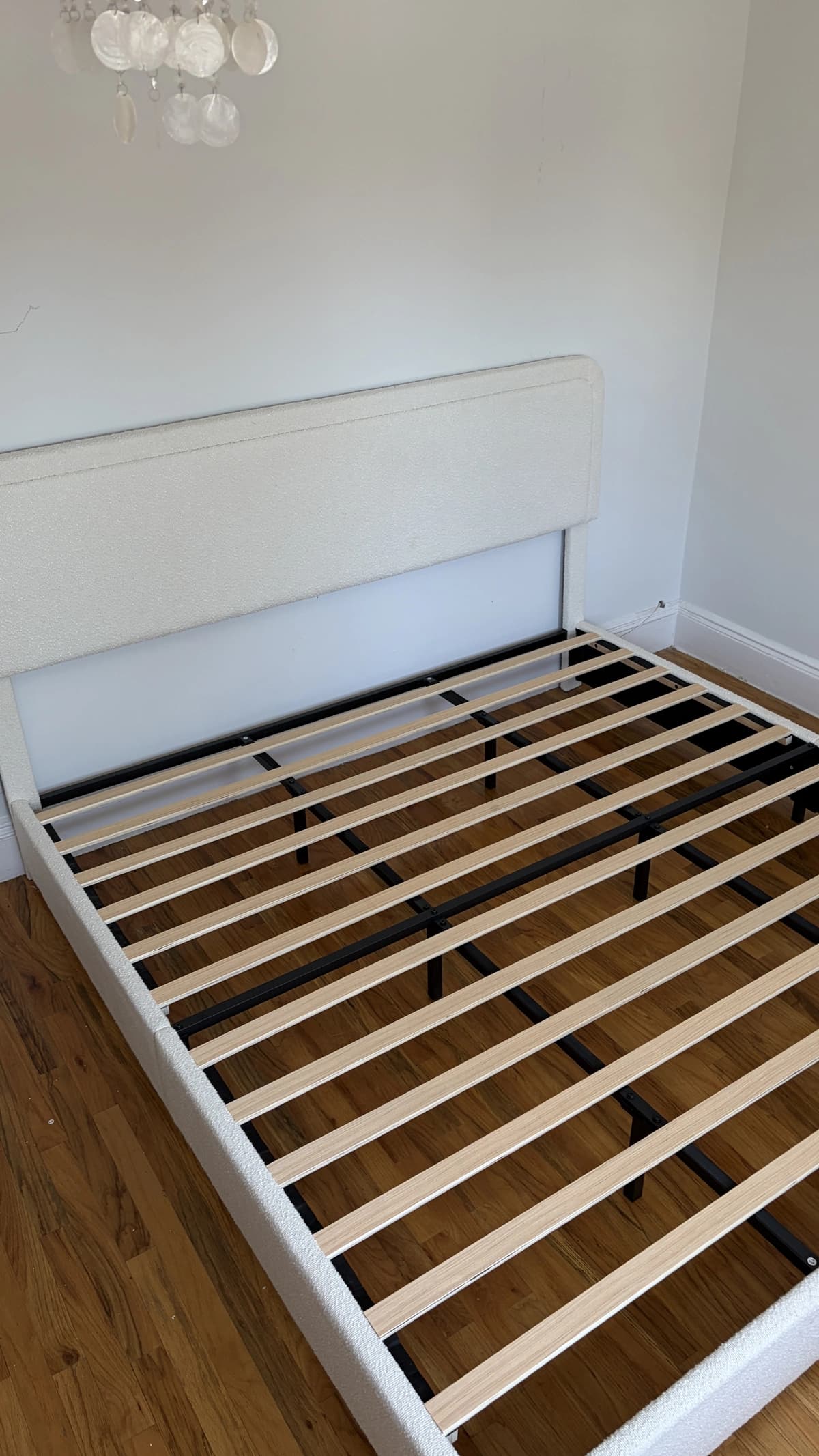 Assembled white upholstered platform bed frame in a bedroom
