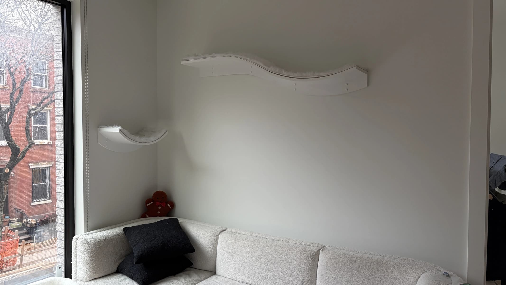 Curved wave-shaped floating shelves mounted on the wall above a sofa