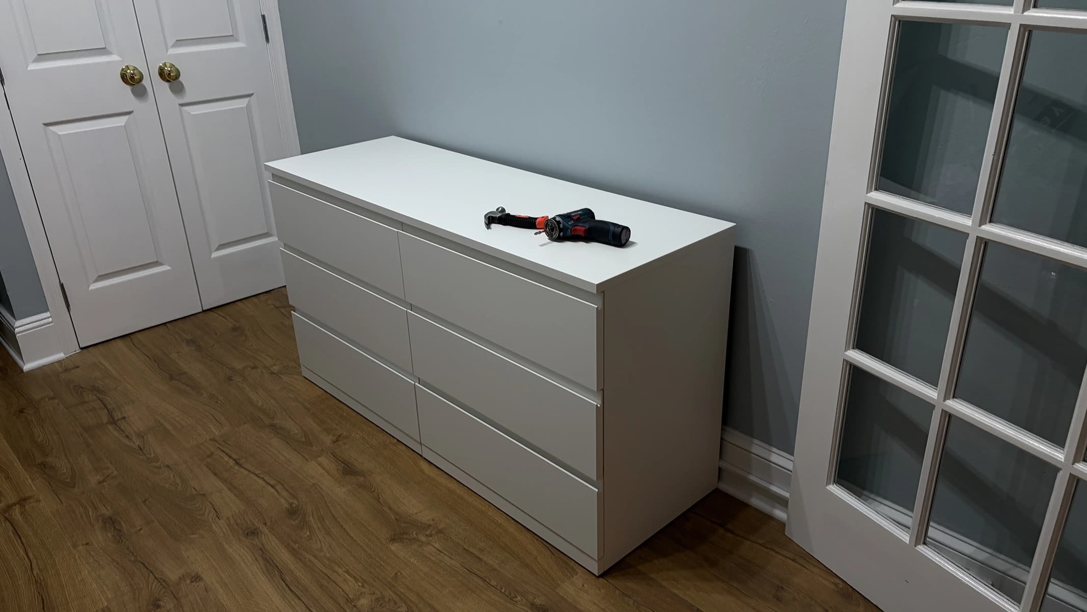 Assembled white six-drawer dresser placed against a bedroom wall