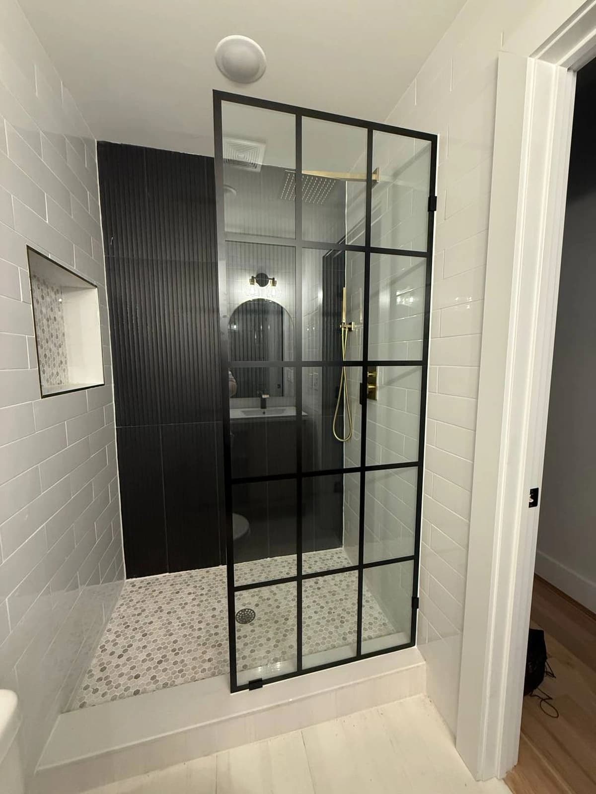 Black-framed glass shower door installed in a tiled walk-in shower