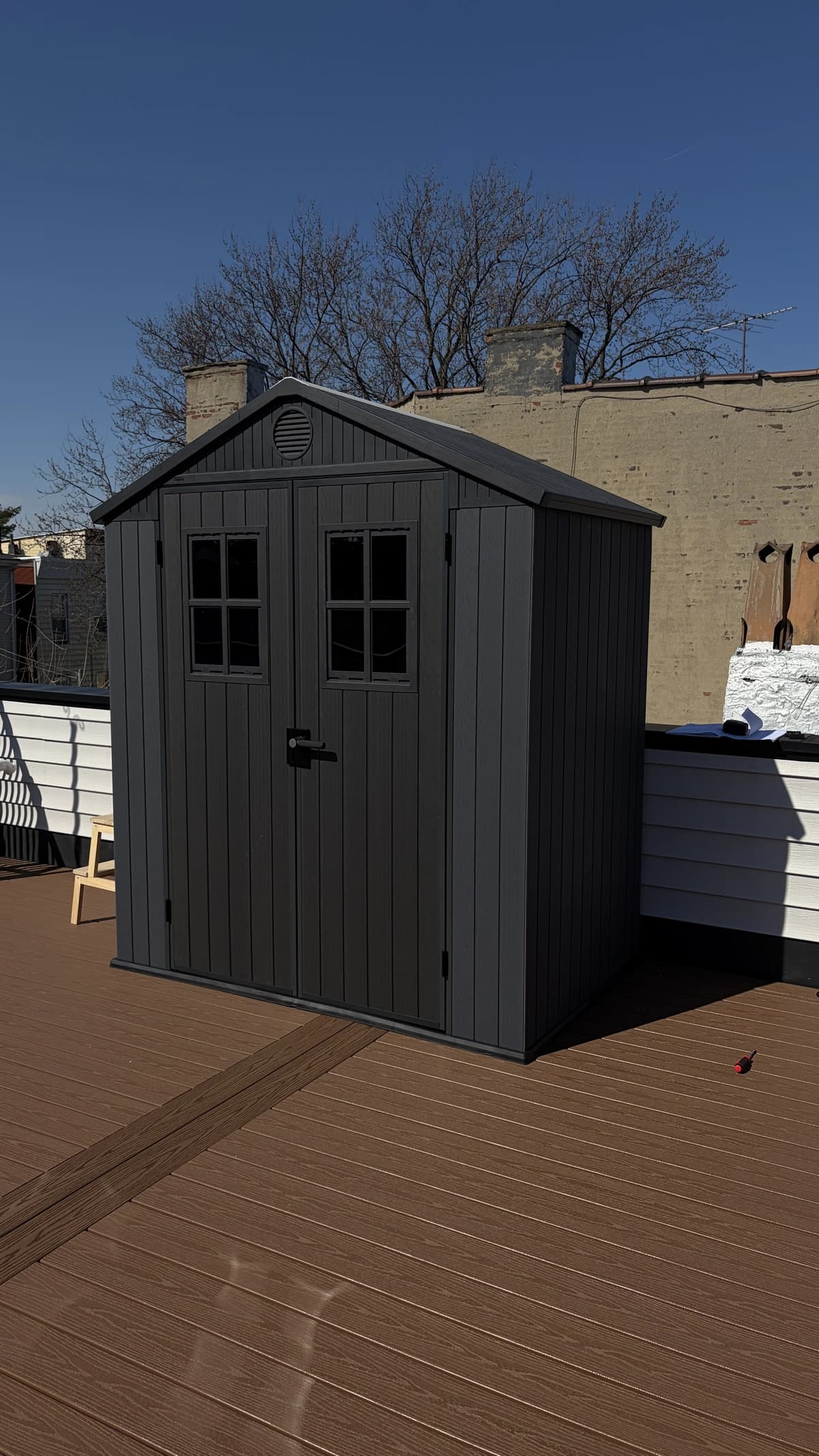 Assembled grey outdoor storage shed on a composite rooftop deck